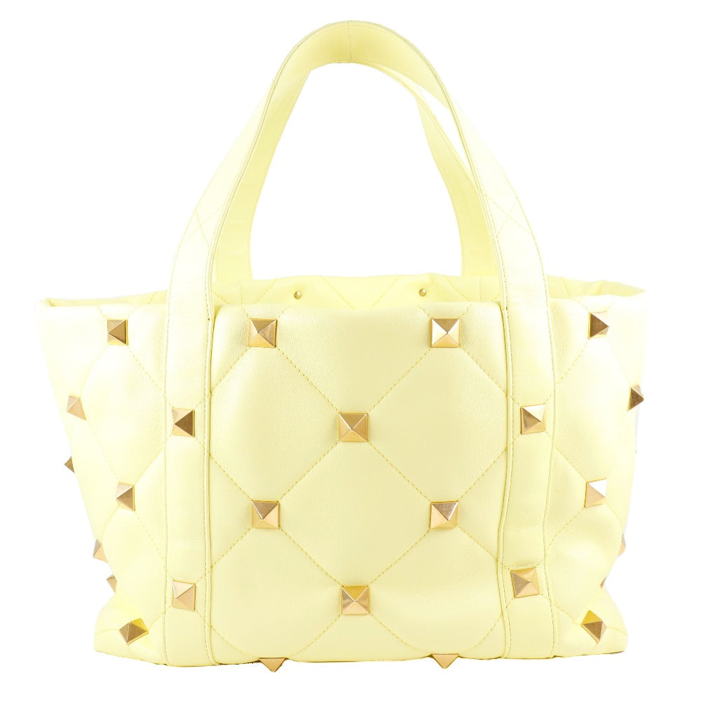 Yellow quilted handbag with gold studs on a white background