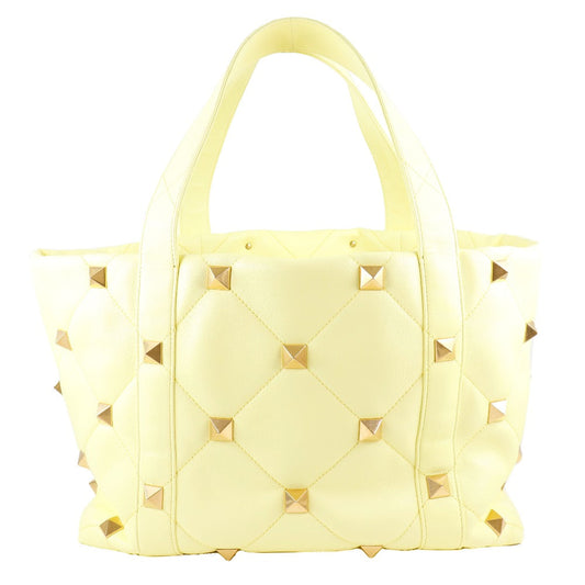 Yellow quilted handbag with gold studs on a white background