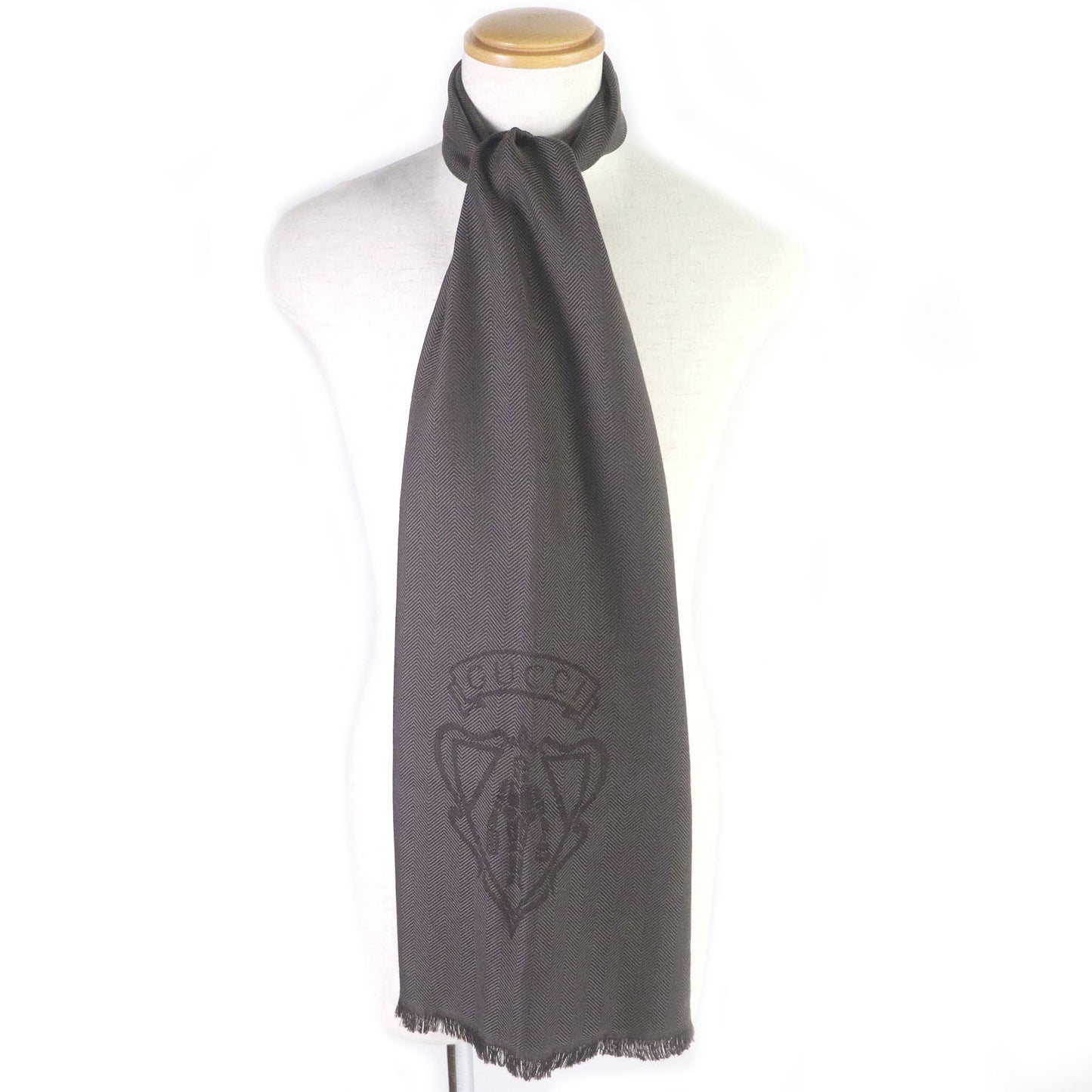 Gray scarf with a GUCCI brand logo on a mannequin against a white background